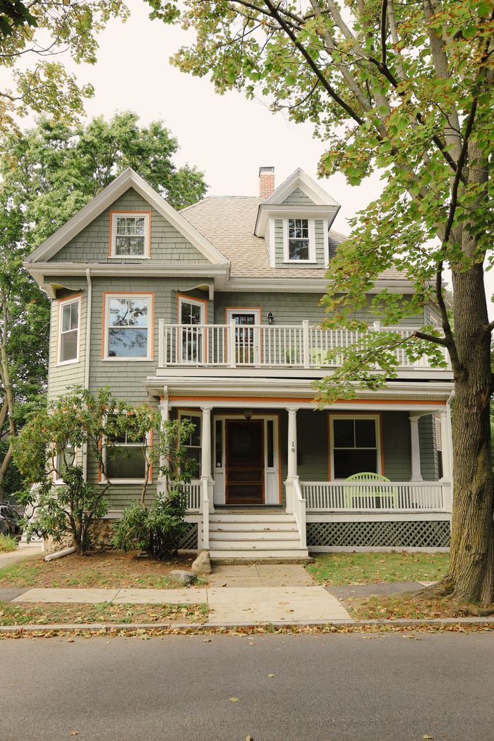 hero-img-02 Elegant Victorian style house with lush greenery and porch in summer.